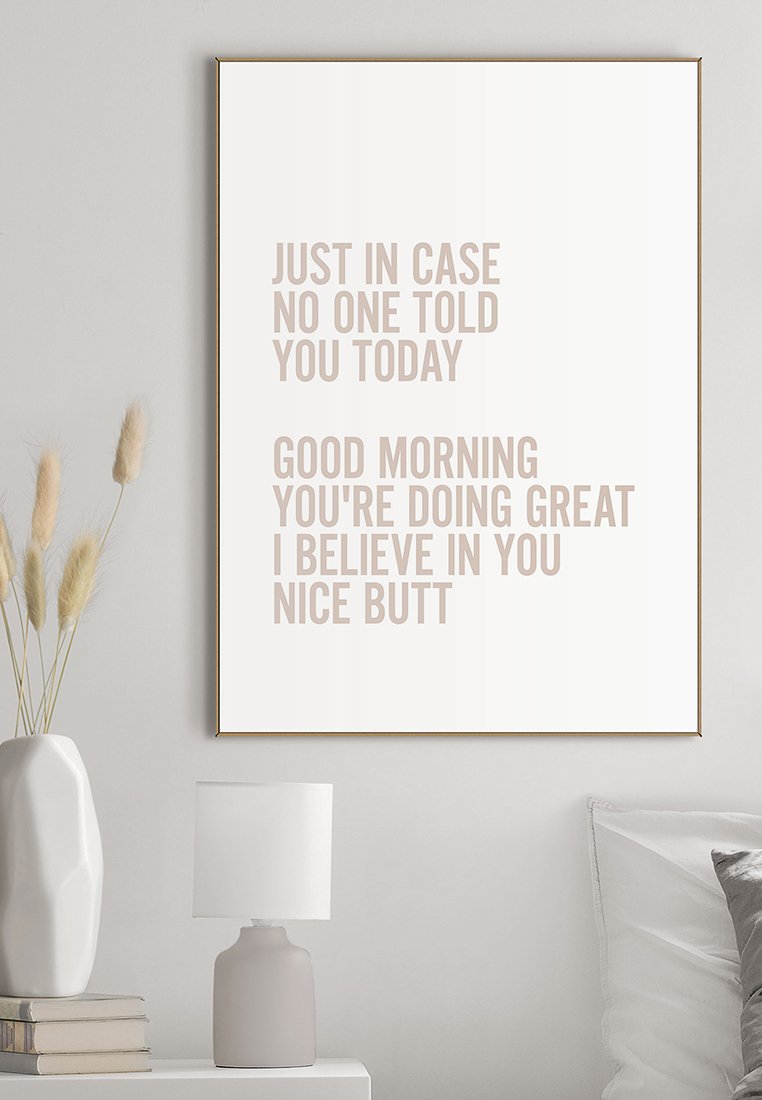 Motivierende Wandkunst in einem modernen Raum liest: "Falls dir heute noch niemand gesagt hat: Guten Morgen, du machst das großartig, ich glaube an dich, schöner Hintern."