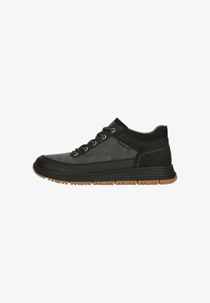 Svarta och grå sneakers med ett överdel av slät läder och textilier med struktur. Utrustad med metallhål, runda snören och en brun gummisula.