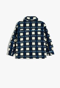 Camisa de forro en crema con un patrón de cuadro en azul y marrón, con cuello y mangas largas, puños abotonados y un corte relajado.