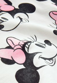 Tissu en coton avec des illustrations répétées de visages de personnages de dessin animé en noir et rose sur un fond blanc. Texture douce.