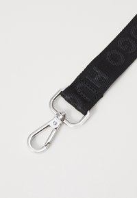 Czarny materiałowy pasek o teksturowanej powierzchni z wytłoczonym napisem, z metalowym zapięciem w kolorze srebrnym.