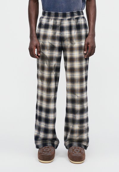 Pantalons de salon à carreaux avec un mélange de couleurs crème, marron et noir, fabriqués en tissu doux avec une taille élastique et des jambes larges.