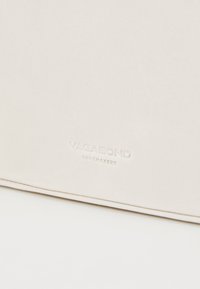 Ljust beige strukturerad läder med präglad "VAGABOND SHOEMAKERS" logotyp. Slät yta och subtil glans. Rektangulär form med rena kanter.