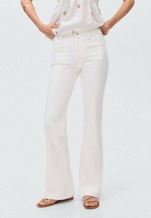 Jeans acampanados blancos de denim, con dos bolsillos traseros y una textura suave. Combinados con una blusa clara y sandalias planas.