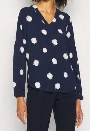 Marineblauwe blouse met witte verfachtige polkadots, V-hals, lange mouwen en geplooide manchetten. Zachte, lichtgewicht stof met een ontspannen pasvorm.