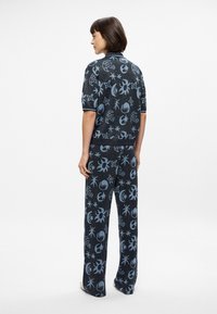 Πλεκτό σετ loungewear σε σκούρο μπλε με ανοιχτό μπλε ουράνια σχέδια; κοντομάνικη μπλούζα και παντελόνι με φαρδιά ποδιά και χαλαρή εφαρμογή.