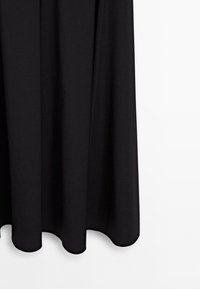 Černé šaty s volným designem, hladkou texturou a zaobleným lemem. Mají měkkou látku, která se elegantně splétá. Žádné viditelné vzory ani akcenty.