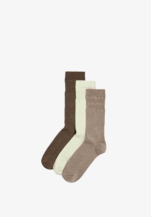 Tre par mellem-kalv strikkede sokker i brun, off-white og lys taupe, hver med en tekstureret ribbet kantmønster.