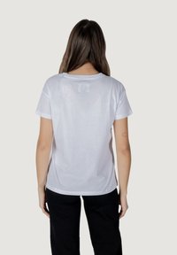 Biała bawełniana koszulka, krótki rękaw, okrągły dekolt, luźny krój, gładka tekstura, minimalistyczny design bez widocznych logo czy akcentów z tyłu.