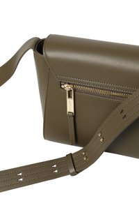 Olivengrøn lædertaske med magnetisk klap, ekstern lynlåslomme, guldfarvet hardware og justerbar rem med perforerede detaljer.