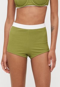 Olivegrønne ribbede shorts med en hvid elastisk talje, med et tætsiddende design og glat tekstur.