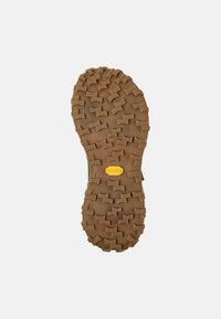 Semelle en caoutchouc avec un motif de bande de roulement distinctif, comprenant des rainures et des crampons. Logo Vibram jaune visible, couleur marron. Surface texturée.