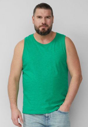 Débardeur en coton vert sans manches avec un col rond, présentant une texture subtile. Associé à un jean en denim bleu clair.