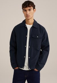 Marineblauwe button-up jas met een kraag, enkele borstzak en drukknoopsluiting. Gladde stof met een relaxte pasvorm en lange mouwen.