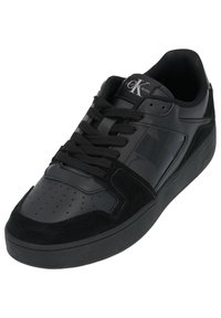 Sneaker nera con tomaia in pelle liscia e accenti in camoscio, punta rotonda, suola in gomma testurizzata e design con lacci. Logo Calvin Klein visibile.