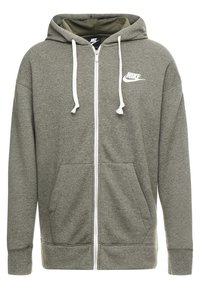 Grauer Reißverschluss-Hoodie aus weichem Stoff. Mit einem weißen Nike-Logo auf der Brust, verstellbaren Kordeln und Fronttaschen.