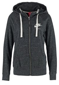 Sudadera con cremallera de color gris oscuro, hecha de tejido texturizado, que presenta un logo blanco, capucha ajustable y dos bolsillos frontales.