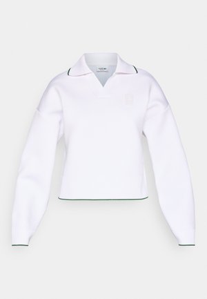 Sweat-shirt blanc court à col en V, manches longues et accents de col verts. Présente un logo texturé sur le devant et des poignets côtelés.