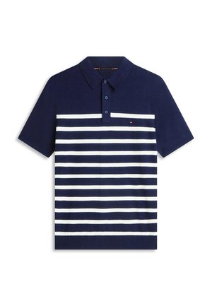 Laivastonsininen poolopaita, jossa valkoiset vaakaraitoja, lyhyet hihat ja napillinen kaulus. Rinnassa pieni logo.