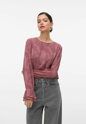 Top a maniche lunghe di colore malva con un tessuto strutturato. Presenta maniche larghe con polsini arricciati. Abbinato a pantaloni a vita alta con motivo.