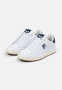 Białe skórzane sneakersy w low-top designie, z granatowym akcentem na pięcie oraz logo marki na języku i boku. Gumowa podeszwa.