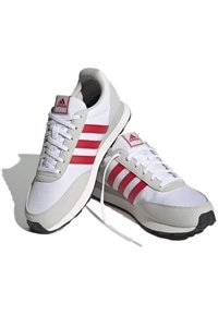 Weiße und graue Sportschuhe mit roten Streifen, ausgestattet mit einer gepolsterten Zunge, Schnürsenkeln und einer strukturierten Gummisohle für besseren Halt.