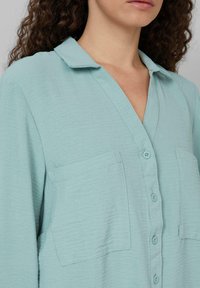 Hellblaues Hemd mit Knopfleiste aus strukturiertem Stoff, mit Kragen, zwei Brusttaschen und einem entspannten Schnitt.