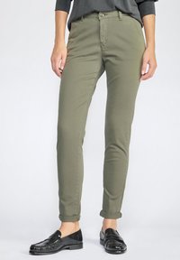 Olive green, slim-fit trousers made of cotton blend fabric, featuring a button closure, belt loops, and cuffed ankles. Paired with black loafers.