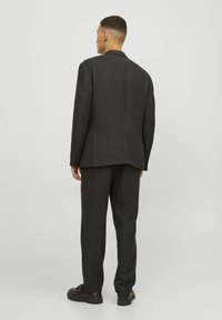 Completo scuro in tessuto misto lana, caratterizzato da una vestibilità sartoriale e pantaloni dritti, accentuato da sottili fibre multicolori.