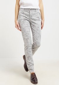 Ljusgrå byxor med ett blommönster, som har en slim fit, bälteshällor och framfickor. I kombination med mörkbruna skor.