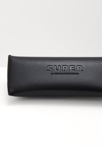 Mustast nahkprillide karp, millel on זעלatud "SUPER" logo. Sellel on ristkülikukujuline kuju, sile pind ja õmmeldud servad.