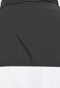 Black and white color-blocked jacket with a smooth fabric texture and a high collar. Features a clean, minimalist design with no visible hardware.