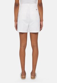 Pantaloncini bianchi in cotone con vestibilità slim, dotati di due tasche posteriori e passante per cintura. Il tessuto appare liscio con una finitura a bordi puliti.