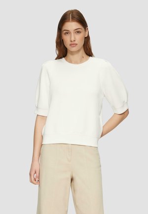 Valge lühikeste varrukatega pullover ümmarguse kaelusega, volüümikate varrukatega ja soonikkäärtega. Materjal näeb välja sile ja veidi veniv.