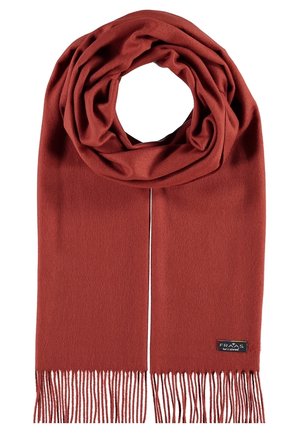 Weicher, rostfarbener Wollschal mit Fransen an den Enden und einem kleinen schwarzen Etikett, das nahe einer Kante angenäht ist.