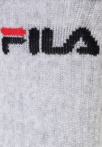 Grå strikket sok med sort og rød "FILA" logo, tekstureret stof, med ribbet manchet og let strækbart materiale.