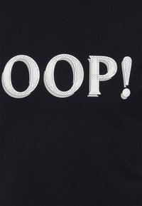 Černá tkanina s velkým bílým nápisem "OOP!" s tečkovanou texturou a jemným šedým stínováním.