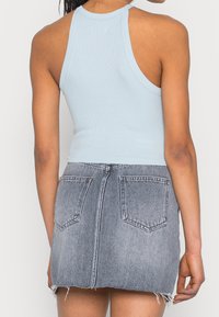 Lysblå ribbet tanktop parret med en grå denim mini nederdel, der har baglommer og frynset kantdetaljer.