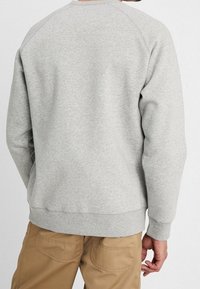 Szary sweatshirt z raglanowymi rękawami, ściągaczami u dołu i na rękawach. Wykonany z miękkiego materiału, charakteryzuje się prostym wzornictwem, bez widocznych logo czy wzorów.