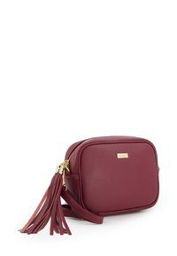 Burgundy faux leather crossbody bag with gold hardware, zip closure, square shape, and a tassel accent on the side.