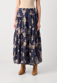 Marineblå blomstrete maxiskjørt med lagdelte volanger, laget av lett stoff, med smocket midje og subtile blomstermønstre. Brune ankelstøvler.