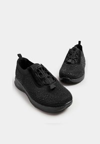 Svarta träningsskor med en strukturerad ovandel med rhinestones, elastiska snörningar och en vadderad svart sula.