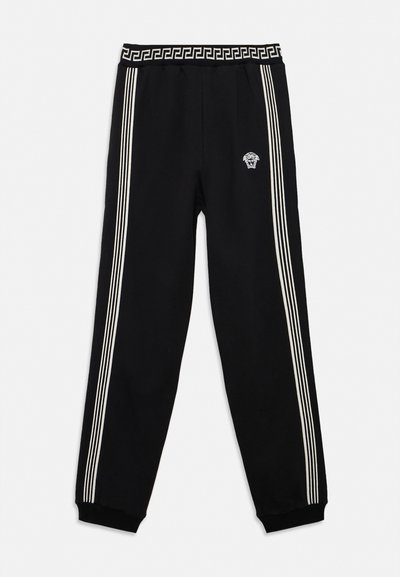 Black track pants with white triple side stripes, elastic waistband featuring a Greek key pattern, and a small white Medusa logo on the front.