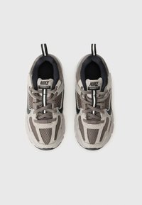 Nike Vomero 5 Sneakers in Grau und Schwarz. Hergestellt aus Mesh- und synthetischen Materialien, mit einem Schnürdesign, Zugschlaufe und strukturiertem Sohlenprofil.