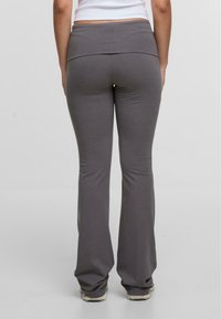 Pantalons de yoga gris ajustés avec une large ceinture, design à jambes évasées, texture douce et sans motifs ni accents visibles.