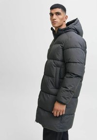 Abrigo acolchado gris oscuro con capucha, que presenta un diseño acolchado, cremallera frontal y bolsillos laterales; textura suave y ajuste ceñido.