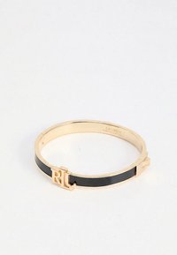 Guld- och svart metallarmband med RL-logga som spänne och slät yta, liggande plant på vit bakgrund.