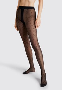 Collant neri trasparenti con un motivo testurizzato di piccole linee verticali. La vita è dotata di un cinturino nero solido e la zona della punta è rinforzata.