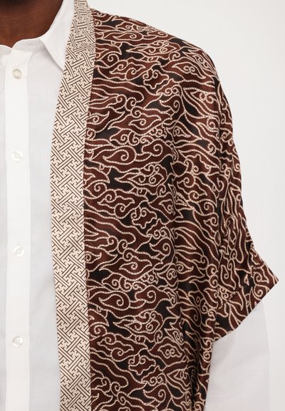 Brunmønstrede kimono med svirvlende hvite design, med en kontrasterende lys beige trim med geometrisk motiv, laget av glatt stoff.