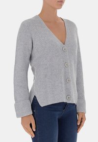 Cardigan grigio a coste con scollatura a V, cinque bottoni sulla parte anteriore e polsini ripiegati. Il tessuto ha una consistenza morbida e una leggera elasticità.